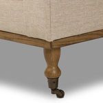 Close-up of turned oak leg with brass caster wheel attached at bottom