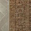 Top-down view of Heritage Clay rug edge highlighting intricate pattern and edge finishing on neutral-toned tile floor