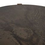 Close-up of iron table top with matte uneven finish and wood pegs on rim
