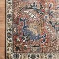 Close-up of a rug corner highlighting the tightly stitched edge and floral pattern.