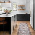 Long runner version of Wynter Red Multi Rug placed in kitchen with black cabinetry and light wood floor.