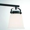 Close-up on one white opal glass shade suspended by matte black metal bracket and screws