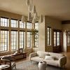 Rug styled in living room with modern beige sofa, armchair, wood floors, and large windows