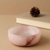 Side view of bowl placed on beige surface next to closed book and small pinecone accent