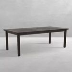 Black aluminum rectangular outdoor dining table in minimalist indoor setting with gray concrete floor and wall