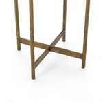 Close detail of the raw brass-finished aluminum frame connecting the legs of the Adair table