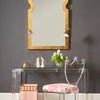 Side view of chair with pink patterned fabric seat positioned by acrylic console and large decorative mirror