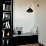 Wall sconce installed in a cozy nook with cushioned bench and bookshelf