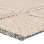 Close-up on wool pile texture and gray fringe along edge of the striped rug