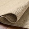 Close-up of curled edge highlighting the woven wool and cotton texture of the rug