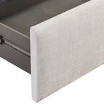 Close-up of light beige fabric upholstery on storage drawer front with metal slide hardware