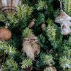 Single owl sculpture nestled among ornaments on a green Christmas tree branch