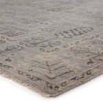 Close-up of gray rug corner showing thick wool texture and natural fringed edge