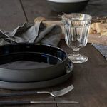 Lagoa Eco Gres bowl paired with matching plate, set with glass, fork, and rustic linen on wooden table