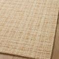 Detailed view of Polly Straw rug pile and weave texture on smooth wood floor surface