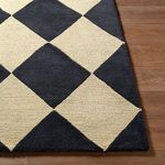 Detailed close-up showing the contrast between the plush charcoal and looped beige wool texture at rug’s corner
