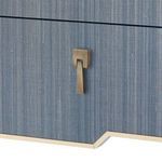 Close-up of brass drawer handle with geometric design on navy blue textured grasscloth drawer front