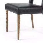 Lower front corner of seat with tightly wrapped smoke-black leather and visible wood leg