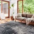 Samra Charcoal Silver Rug in a modern living room with large windows, wood floors, and light brown sofa
