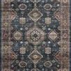 Traditional-style area rug with geometric motifs in distressed navy blue, peach, beige, and light blue tones
