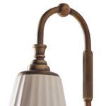Close-up of swan neck arm showing ribbed brass detailing and ball finial near ceramic shade
