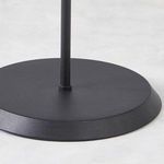 Close-up of textured black circular metal base and base of lamp pole on white surface