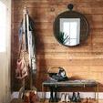 Mirror in an entryway with rustic wood plank wall, bench, boots, and coat rack