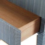 Drawer pulled open showing smooth light natural wood interior contrasting navy grasscloth exterior