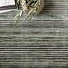 Close-up of Bellamy Lagoon Rug showing texture and a ceramic vase with greenery and book stack.