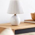 Ferez lamp styled on wooden surface next to books and wooden bowl in bright room