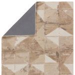 Rug corner folded back to reveal solid grey backing contrasting with taupe geometric pattern