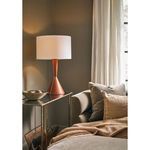 Denver Leather Table Lamp lit, sitting on a side table with cushioned sofa and basket underneath