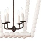 Lower side view focusing on the lamp’s curved metal candle arms and the rounded wood beads