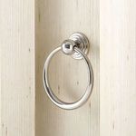 Close-up of a polished silver ring pull handle mounted on the rippled drawer front