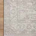 Top-down close-up of rug edge on wood floor showing textured woven pattern and border