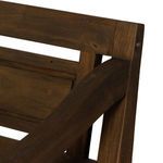 angled side view showing the pointed leg design and rustic carved armrest from front left