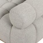 Close-up of light grey tufted fabric upholstery with visible fine weave texture on rounded edges