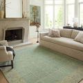 Rug placed in a bright living room with beige sofa, cream fireplace, and natural light through windows