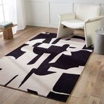 Rug staged in room under neutral armchair on light hardwood flooring