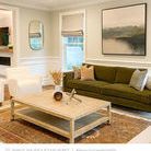 Misty Lake II painting hanging above olive green sofa in bright living room with neutral walls and light wood coffee table