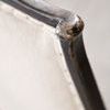 Close-up of curved top corner with distressed black finish and nail-head trim detail on soft fabric