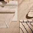 Close-up showing raised shag texture and folded corner of Stria Outdoor Rug on diagonally striped background