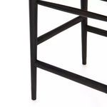 Close-up of black teak leg and connecting stretchers supporting woven seat