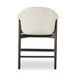 Back view showing tapered legs, black footrest and boucle upholstery wrapping