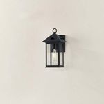 Outdoor wall sconce mounted on a beige wall, shown from a slight side angle revealing depth.
