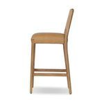 Side profile highlighting the chair’s slim wood legs and softly upholstered seat
