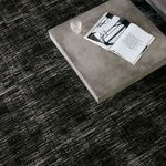 Close-up of rug texture under concrete square coffee table with glass and book on top