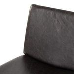 Angled close-up of padded black leather backrest with visible natural texture