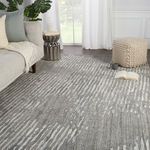 Striped light gray rug styled in bright living room with sofa, pouf, and natural light
