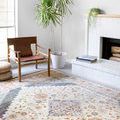 Rug in a bright room setting with mid-century chair, potted plant, and white brick fireplace